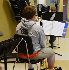 Student musician reads music and sits with his instrument